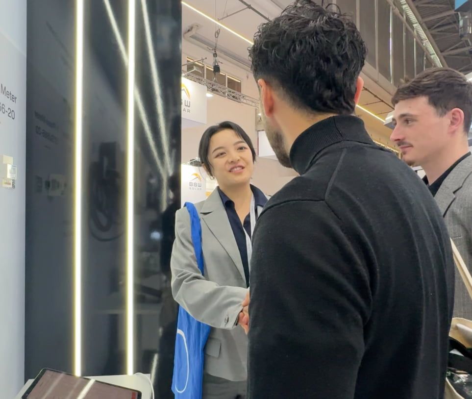 Drei Personen begrüßen sich auf einer Messe.